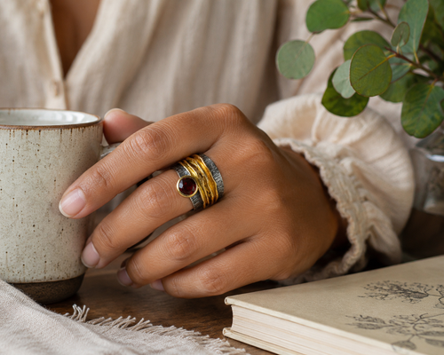 Artisan garnet ring worn on hand featuring a deep red garnet gemstone with oxidized sterling silver and layered gold vermeil accents