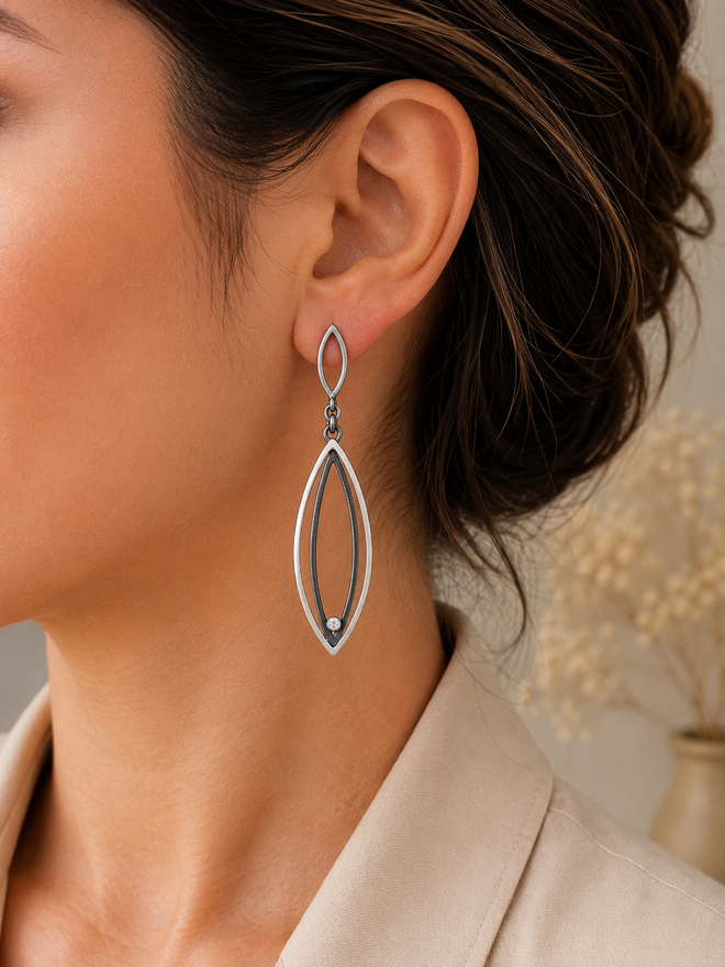 Handcrafted two-tone sterling silver earrings with oxidized silver details and cubic zirconia displayed in an elegant jewelry setting at Raku Gallery in Jerome Arizona.
