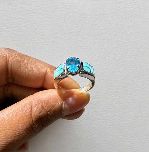 Close-up of an authentic Navajo sterling silver ring with Kingman Arizona turquoise inlay and a faceted blue topaz gemstone.
