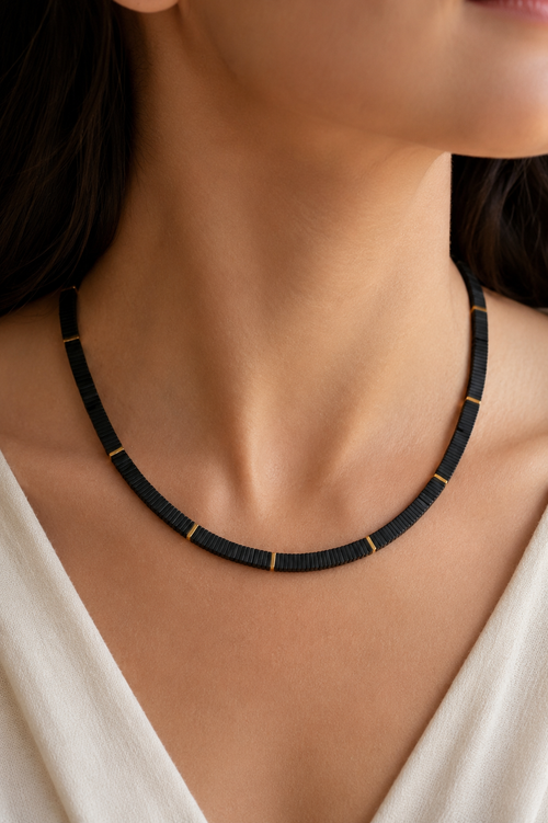 Model wearing an 18-inch handmade black hematite necklace with 6x6mm square beads and 18K gold-plated sterling silver accents. Modern minimalist jewelry for everyday wear and layering.