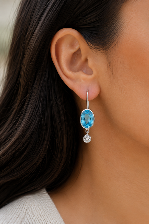 Model wearing handmade Blue Topaz and White Topaz sterling silver drop earrings showing their elegant everyday size and fit.