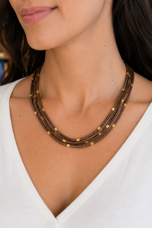 Model wearing a four-strand brown hematite necklace with 2mm square-cut beads and gold-plated sterling silver accent beads, shown at an 18-inch length.