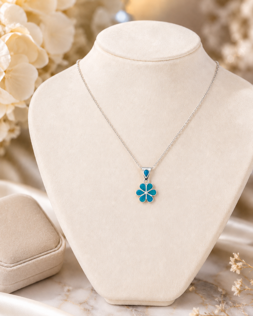 Chrysocolla flower pendant necklace displayed on cream jewelry bust in a luxury setting with sterling silver chain