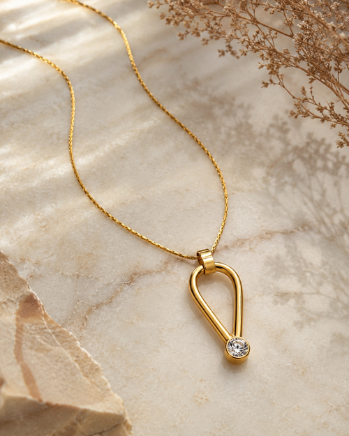 Gold vermeil pendant necklace with modern sculptural design and cubic zirconia detail.