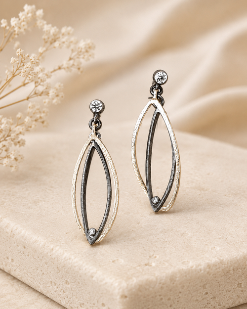 Contemporary oxidized sterling silver marquise earrings with cubic zirconia accents shown on ear for size reference and styling inspiration