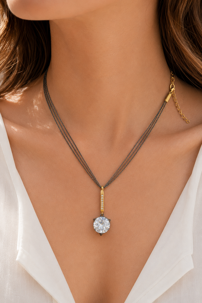 Elegant layered crystal necklace worn on a model featuring three oxidized sterling silver chains, a gold plated sterling silver CZ bar, and a sparkling 12mm crystal pendant.