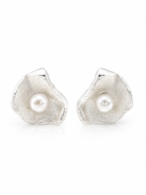 Close-up of designer sterling silver petal stud earrings with genuine freshwater pearls, handcrafted contemporary artisan jewelry with a satin finish inspired by natural flower petals.