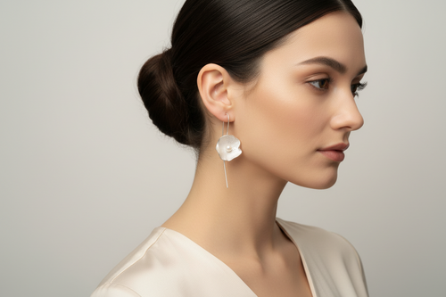 Close-up of a model wearing designer sterling silver flower drop earrings with genuine freshwater pearls and elegant French hook ear wires.