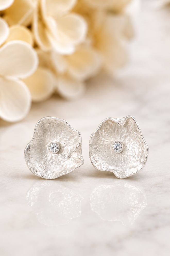 Designer sterling silver petal stud earrings with brilliant cubic zirconia shown on a model. Handcrafted artisan jewelry with a contemporary floral design.