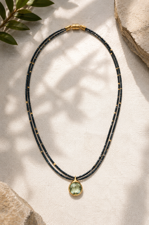Full view of a handcrafted double-strand hematite bead necklace featuring gold-plated accent beads, a 12mm Green Amethyst pendant, and a gold-plated sterling silver magnetic clasp.