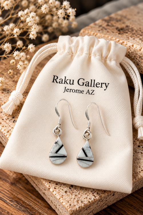Black and white geometric gemstone earrings handcrafted with White Buffalo Turquoise, Black Jade and sterling silver, displayed on a cream Raku Gallery pouch.