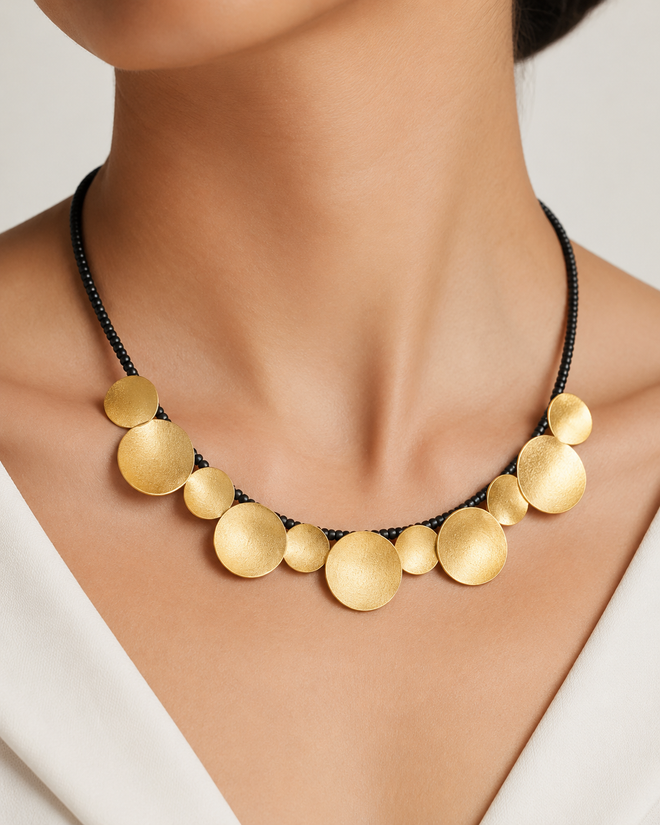 Gold plated disc necklace with black onyx beads shown on a model neck