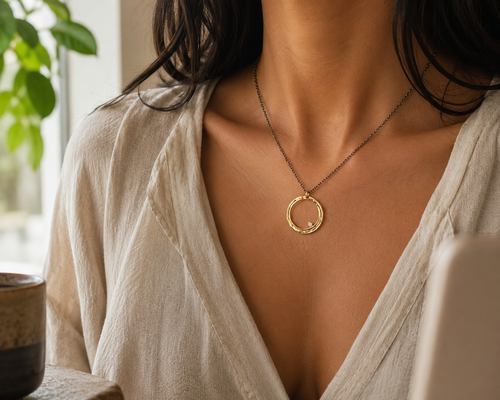 Lifestyle image of gold-filled circle pendant necklace with cubic zirconia and oxidized sterling silver chain