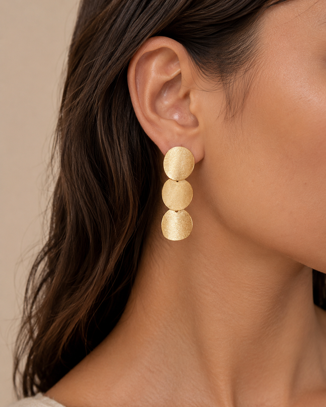 Gold plated sterling silver disc drop earrings shown on ear