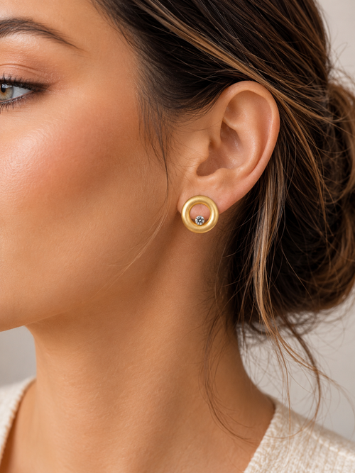 Model wearing contemporary matte gold vermeil open circle stud earrings with sparkling white cubic zirconia, handcrafted sterling silver designer jewelry.