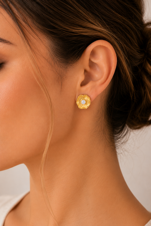 Woman wearing handmade gold vermeil petal stud earrings featuring brilliant 4 mm cubic zirconia, contemporary artisan sterling silver jewelry with an elegant organic floral design.