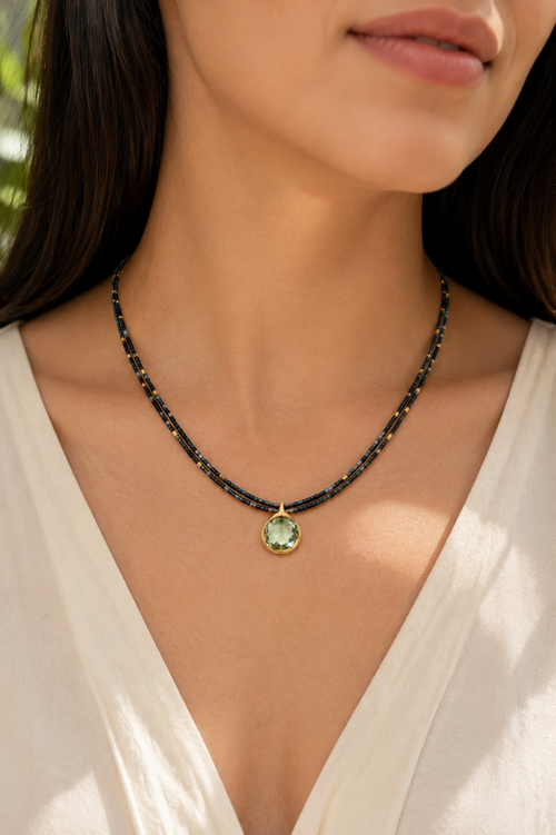 Model wearing a handmade double-strand hematite beaded necklace with a 12mm Green Amethyst pendant in gold-plated sterling silver.