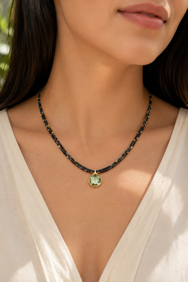 Model wearing a handmade double-strand hematite beaded necklace with a 12mm Green Amethyst pendant in gold-plated sterling silver.
