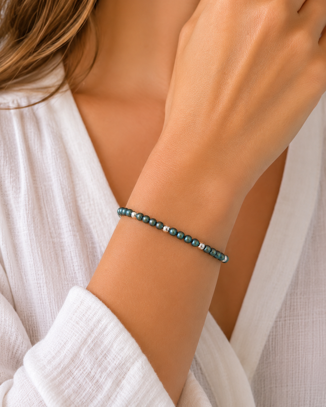 Model wearing a handcrafted matte green-blue hematite bracelet with polished sterling silver beads, elegant minimalist gemstone jewelry for everyday wear.