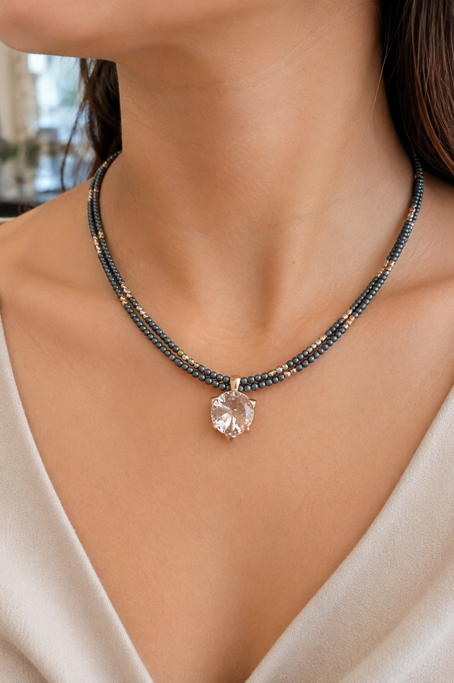 Woman wearing an elegant 18-inch two-strand grey hematite necklace with a sparkling crystal pendant and rose gold plated sterling silver accents.