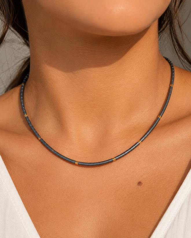 Grey hematite beaded necklace with gold accents worn on a model, showcasing a modern minimalist choker style.