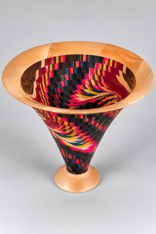 Angled view of Jack Dohallow's handcrafted Vortex Bowl showing intricate layered wood patterns flowing from the exterior into the colorful interior.