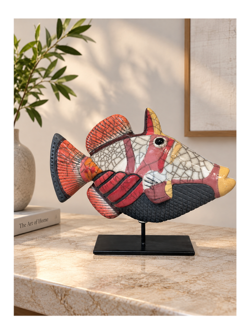 Handmade coral red Raku ceramic fish sculpture displayed on a black metal stand in a contemporary interior