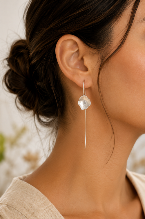 Model wearing handcrafted sterling silver flower drop earrings with long French hook ear wires and sparkling 2mm cubic zirconia.
