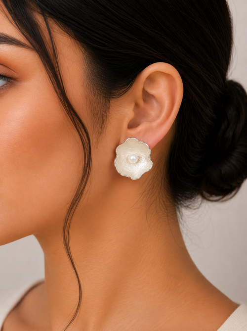 Handmade sterling silver flower stud earrings with genuine freshwater pearls shown on a model, featuring an elegant organic floral design and contemporary artisan craftsmanship.