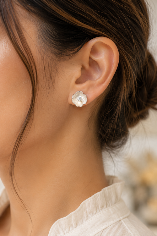 Model wearing handmade sterling silver petal stud earrings featuring brilliant cubic zirconia. Elegant artisan floral earrings styled for everyday wear.