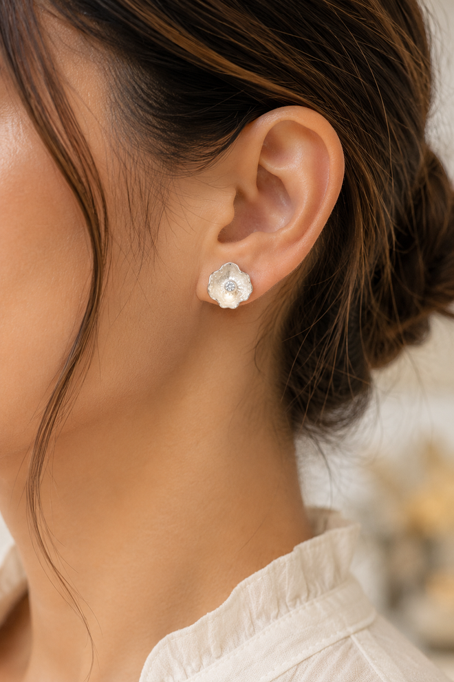 Model wearing handmade sterling silver petal stud earrings featuring brilliant cubic zirconia. Elegant artisan floral earrings styled for everyday wear.