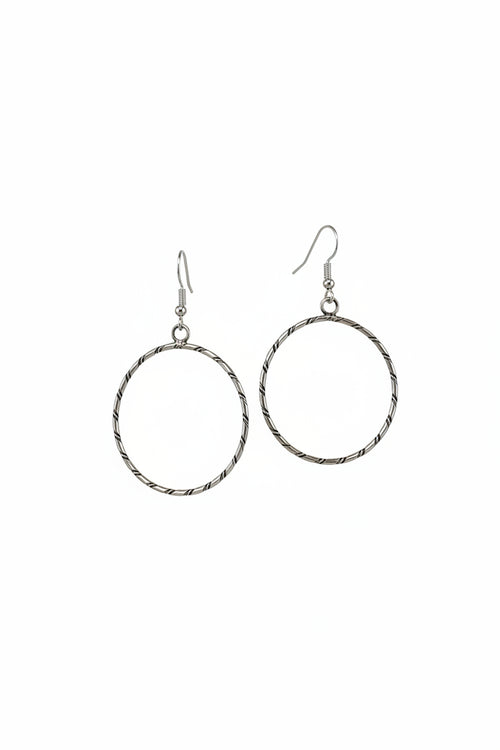 Handmade sterling silver round hoop earrings by Navajo artist Caroline Tsosie with textured silver design.