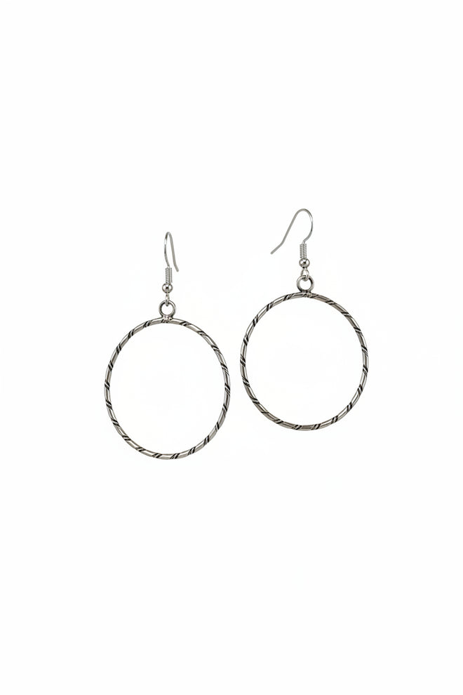 Handmade sterling silver round hoop earrings by Navajo artist Caroline Tsosie with textured silver design.