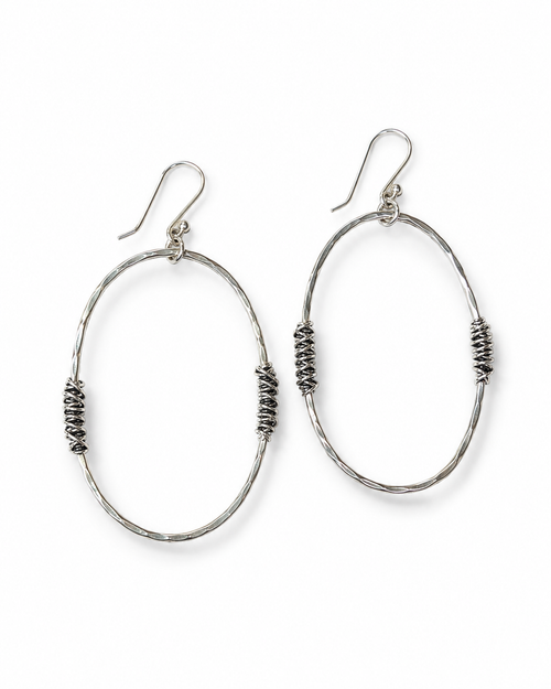 Large hammered silver open oval earrings with wrapped silver detail on a white background