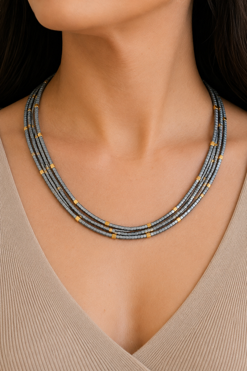 Woman wearing a handmade 4 strand light gray hematite necklace with square cut beads and 18K gold plated sterling silver accents, adjustable 18 to 20 inches.