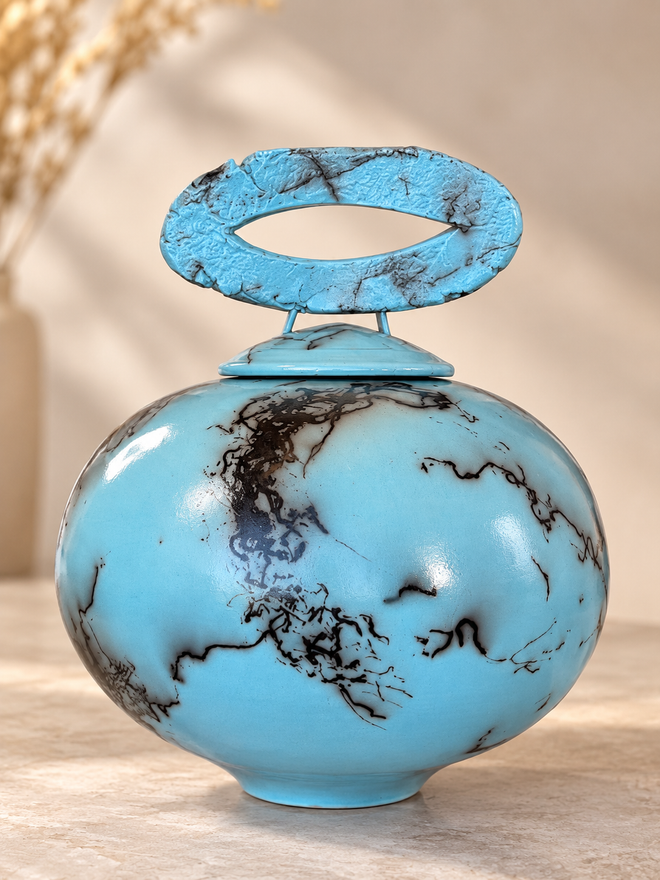 Light turquoise horsehair raku lidded pot with sculptural oval lid and organic black firing patterns