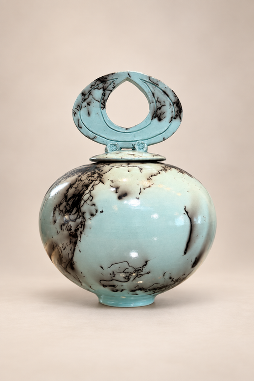 Light turquoise horsehair raku lidded vessel with sculptural loop lid and organic black firing patterns