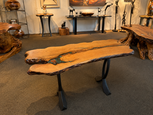 Live edge wood table with turquoise and copper inlay displayed in an art gallery
