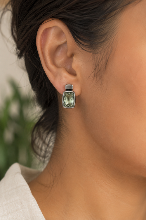 One-of-a-kind handcrafted Green Amethyst stud earrings with 9x12mm faceted gemstones in smooth oxidized sterling silver, photographed in an elegant luxury setting.