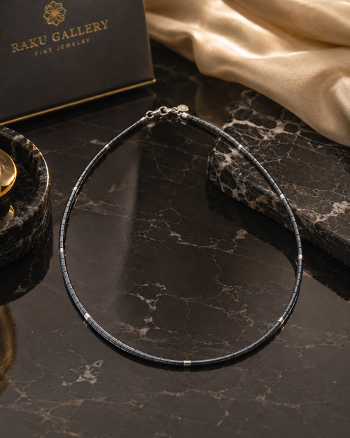 Luxury grey hematite necklace with sterling silver accents displayed on an elegant marble setting.