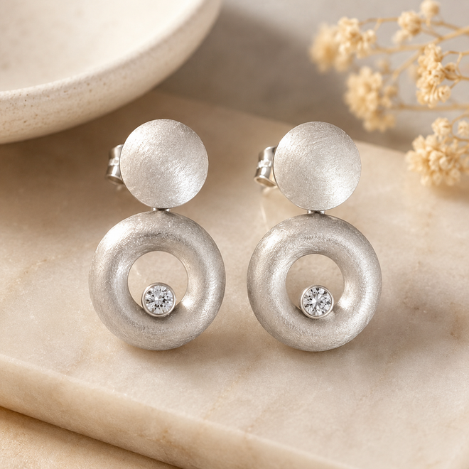 Luxury handcrafted matte sterling silver circle drop earrings with bezel-set white cubic zirconia in a contemporary sculptural design, perfect for elegant everyday wear.