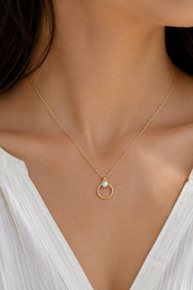Woman wearing a 14K gold-filled freshwater pearl circle necklace with a modern minimalist design and adjustable 16 to 18 inch chain.