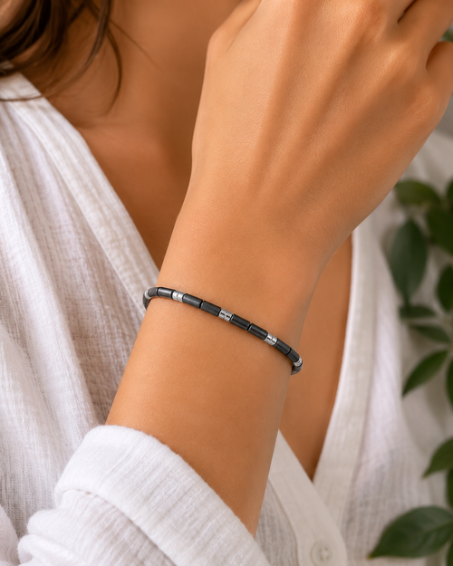 Model wearing a handcrafted graphite hematite cylinder bracelet with polished sterling silver beads, contemporary minimalist jewelry for everyday wear.