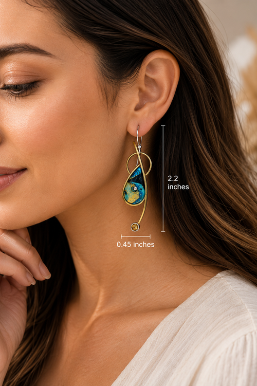 Modern blue designer earrings with citrine accents shown on model ear for size reference.