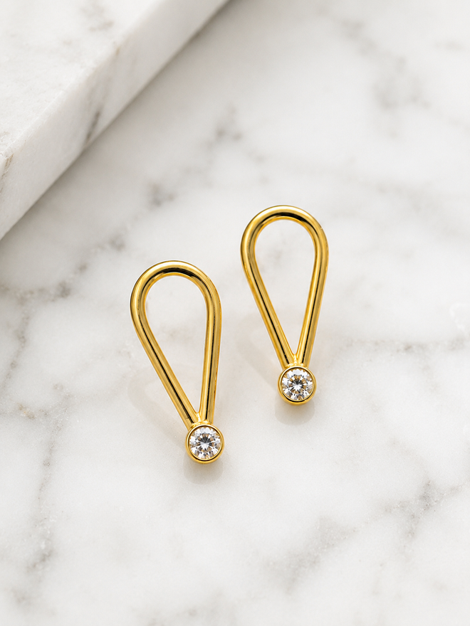 Modern gold loop drop earrings featuring cubic zirconia stones
