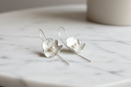 Modern sterling silver drop earrings with genuine freshwater pearls and sculptural flower petals shown on a model, handcrafted artisan jewelry for everyday elegance.