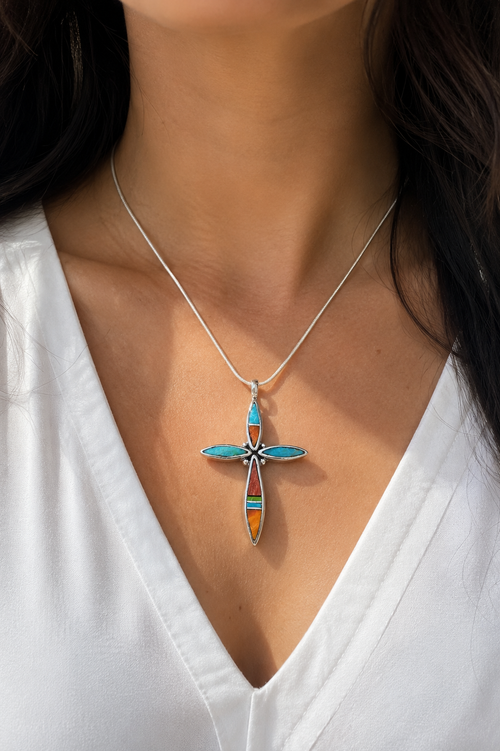 Model wearing an authentic Navajo sterling silver cross necklace with handcrafted turquoise, orange spiny oyster, red jasper, and gaspeite stone inlay, Southwestern Native American jewelry.