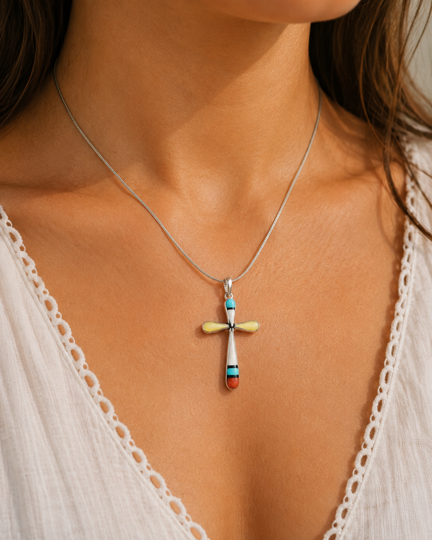 Handcrafted Native American Zuni cross necklace in sterling silver by Sylvester Noche featuring genuine turquoise, mother of pearl, coral, and yellow shell with a sterling silver chain.