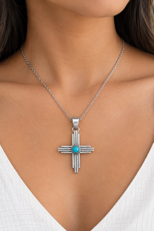 Navajo turquoise sterling silver Four Directions cross pendant shown worn on a necklace