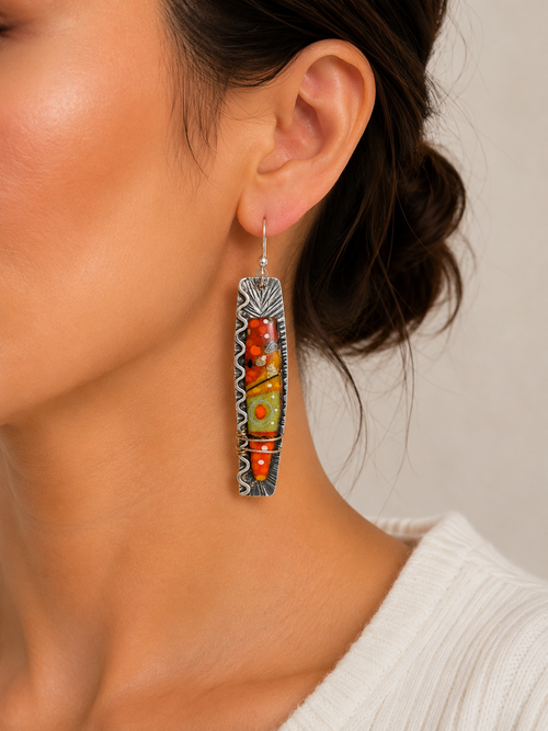 Orange art glass statement earrings shown on model ear for size reference
